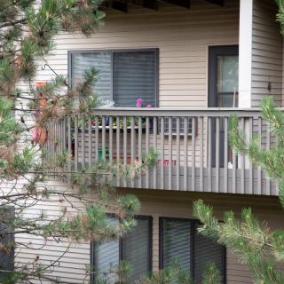 An apartment balcony surrounded by trees and plants.