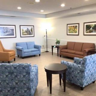 A cozy living room area with various sofas and chairs arranged around a small table, complemented by artwork on the walls.