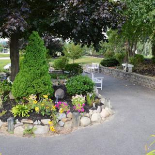 A beautifully landscaped garden with a stone-bordered flower bed and a paved pathway.