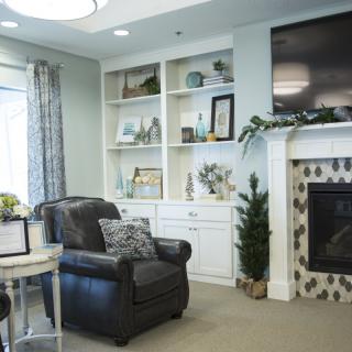 A cozy living room with a fireplace, armchair, and built-in shelves.