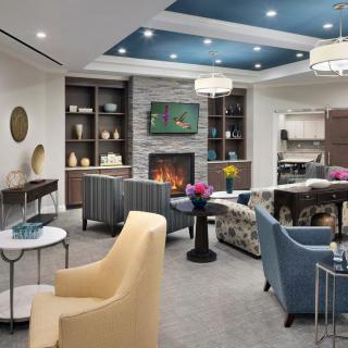 A modern and cozy living room with a central fireplace, various seating options, and stylish decor.