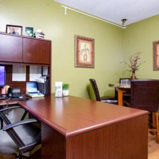 A neatly organized office space with a desk, chair, computer, and decorative elements on green walls.