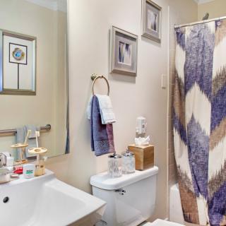 A neatly organized bathroom with a modern sink, toilet, and colorful shower curtain.