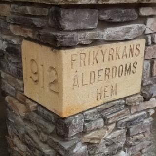 A close-up view of a stone pillar featuring an inscription that reads 'FRIKYRKANS �LDERDOMS DEN' and the year '1912'.