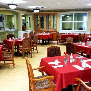 A restaurant dining area with tables covered in red tablecloths and wooden chairs.