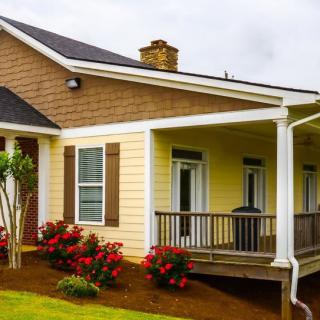 A charming house with a front porch and garden filled with blooming flowers.