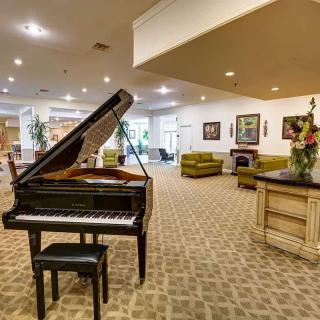 A spacious and elegantly decorated living area featuring a grand piano, comfortable seating, and tasteful artwork.