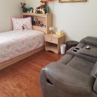 A cozy bedroom with a single bed, side table, and comfortable recliner.