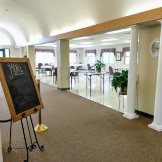 A spacious and well-lit lobby area featuring columns, chairs, and a chalkboard.