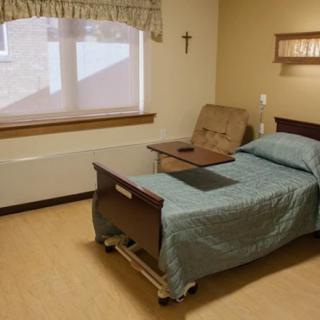 A hospital room with a single bed and a window.