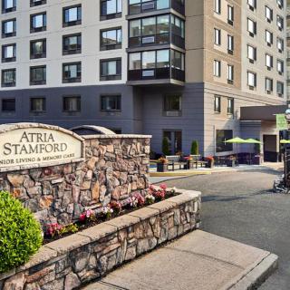 The entrance to Atria Stamford, featuring well-maintained landscaping and a welcoming sign.