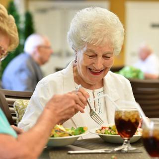 A group of elderly individuals enjoying a meal together in a dining setting.