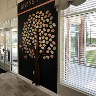 A vibrant wall art featuring a giving tree with colorful leaves, symbolizing generosity and community spirit.