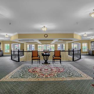 A spacious lobby with a seating area, featuring two chairs and a small table on a decorative carpet.