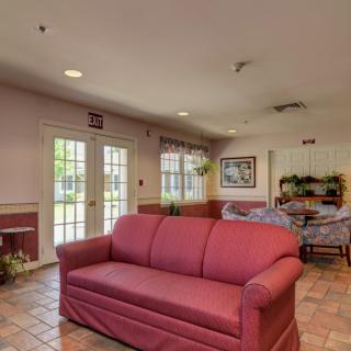 A cozy living room featuring a red sofa, artwork on the wall, and natural light streaming through the windows.