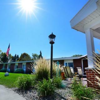 A sunny day outside a building with an American flag and surrounding greenery.
