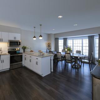 A modern open-concept kitchen and dining area with hardwood floors and stylish lighting.