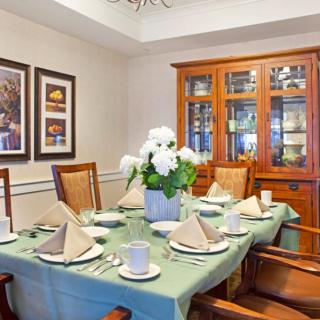 A well-decorated dining room with a table elegantly set for a meal, featuring a green tablecloth and a centerpiece of white flowers.