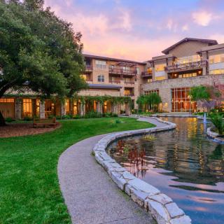 A serene building with a pond and lush garden at sunset.