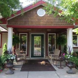A welcoming building entrance with a porch, potted plants, and seating.