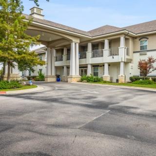 A large building with prominent columns at the entrance and a spacious parking lot.