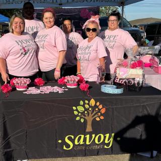 A vibrant team celebrating together at an outdoor event, showcasing their spirit in matching pink shirts.