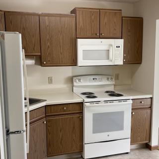 A small kitchen with wooden cabinets and white appliances.