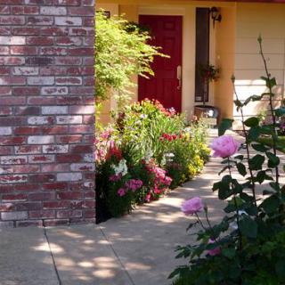 A charming garden pathway leading to a red front door, bordered by vibrant flowers.