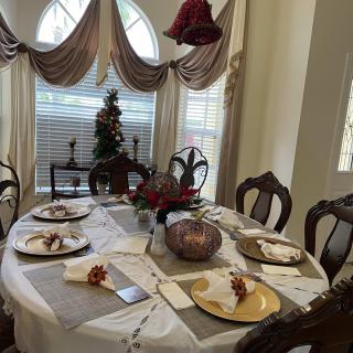 A beautifully decorated dining table prepared for a festive gathering, featuring elegant place settings and holiday decorations.