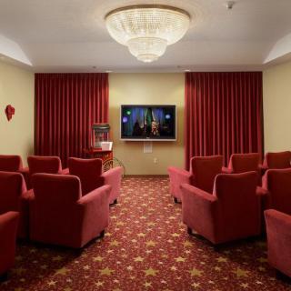 A cozy home theater room with red armchairs, a large screen, and elegant decor.