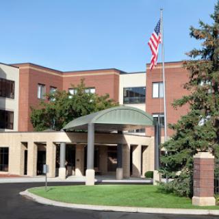 A welcoming entrance to a modern facility, featuring an American flag and landscaped surroundings.