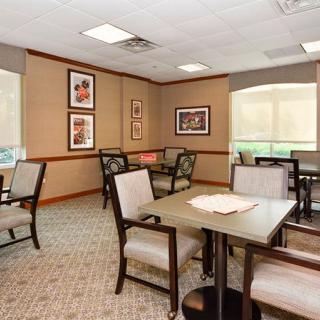 A cozy dining room with several tables and chairs, decorated with framed artwork on the walls.
