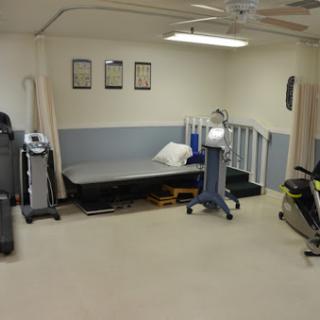 A therapy room equipped with various rehabilitation equipment and exercise machines.