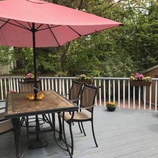 A cozy outdoor patio with a table, chairs, and a red umbrella.