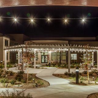 A beautifully lit building at night with a well-defined pathway and surrounding garden.