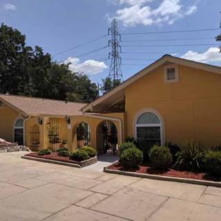 A yellow house with well-maintained landscaping and a driveway on a sunny day.