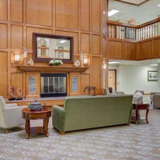 A spacious living room with elegant wood paneling, featuring a sofa set, fireplace, and decorative elements.
