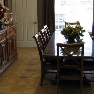 A cozy dining room with a wooden table and chairs, decorated with a floral centerpiece.