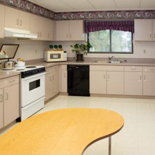 A clean and organized kitchen with a view, featuring modern appliances and a wooden table.