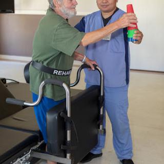 A healthcare professional assists a patient in a rehabilitation exercise.