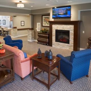 A modern living room with a cozy seating area, featuring a fireplace and television.