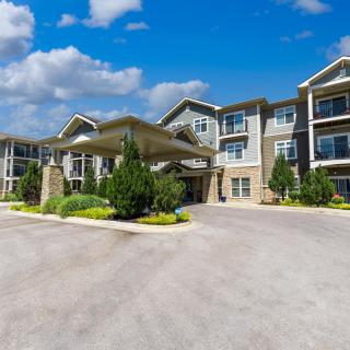 A modern apartment building with well-maintained landscaping under a clear blue sky.