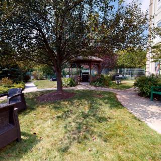 A peaceful garden with a gazebo and benches surrounded by lush greenery.