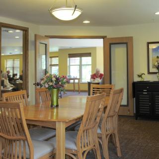 A wooden dining table surrounded by chairs in a well-lit room with decorative elements.