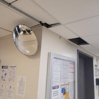 A convex mirror mounted on the ceiling, reflecting part of the room.