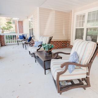 A cozy porch with comfortable seating and potted plants, perfect for relaxation.