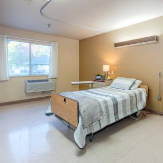 A clean and comfortable hospital patient room with a bed, window, and essential amenities.