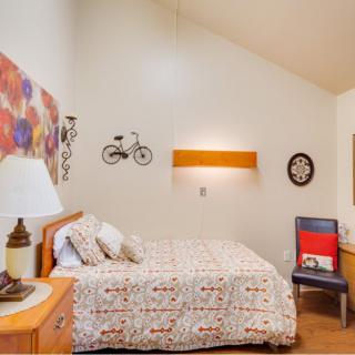 A cozy bedroom with a bed, wall art, and warm lighting.