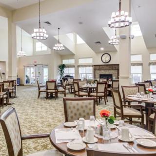 An elegant dining area with neatly arranged tables and chairs, well-lit by chandeliers.