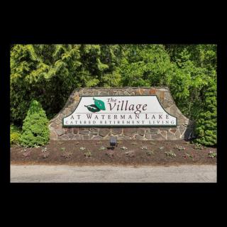 Entrance sign for The Village at Shawnee Lake surrounded by lush greenery.